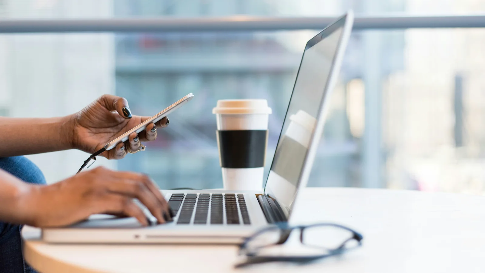 Profissional usando notebook e smartphone para gerenciar atendimento digital