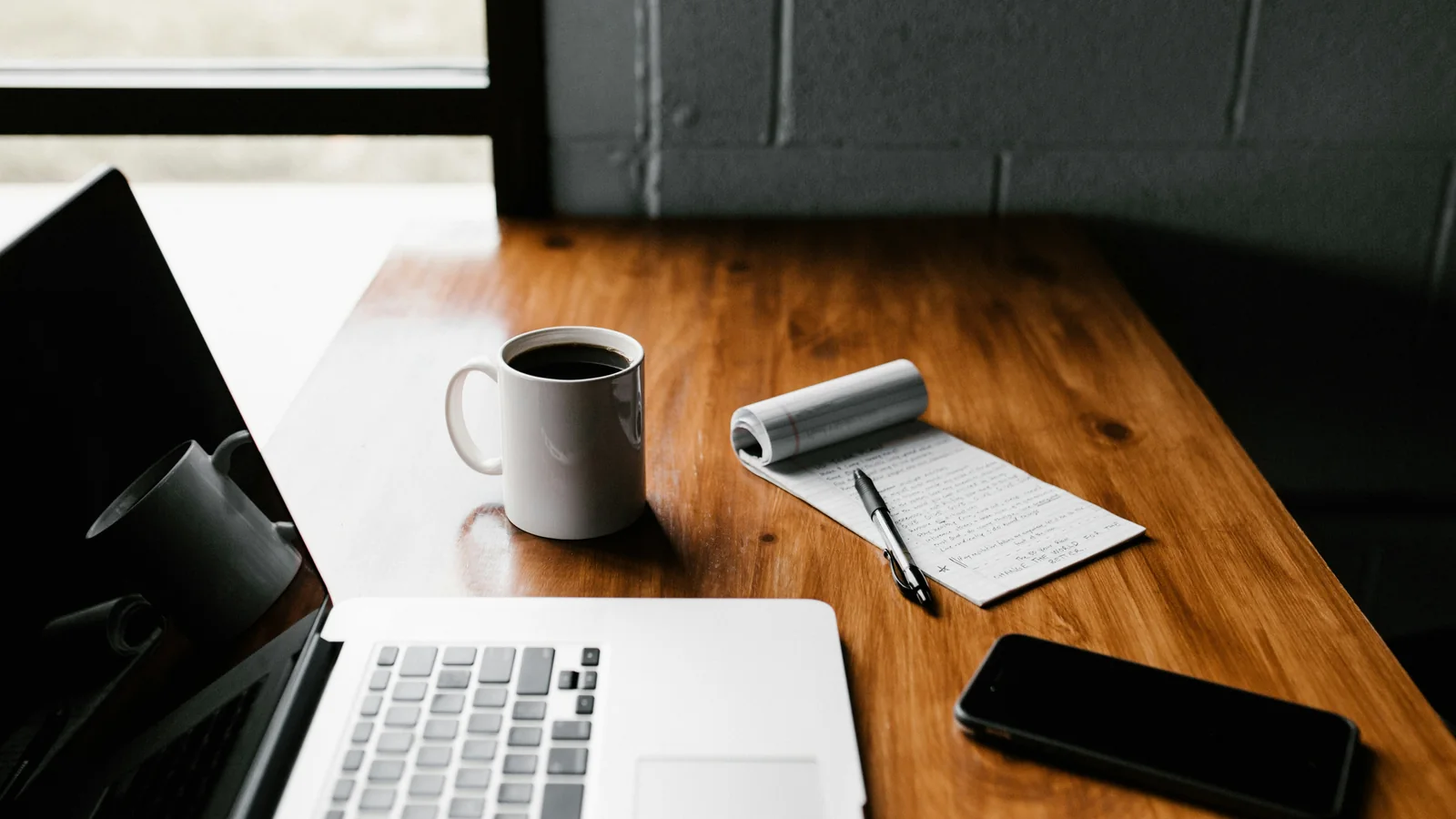 Notebook, smartphone e bloco de notas em uma mesa de trabalho